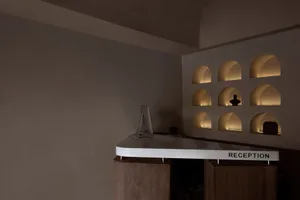 A modern reception desk with concrete material and illuminated shelves.