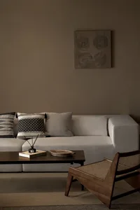 Industrial-style living room featuring a beige sectional sofa with fabric cushions, a wooden coffee table with a book and bow