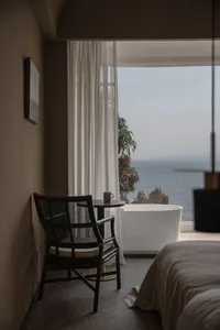 Modern bedroom featuring white furniture and laminate flooring, overlooking the ocean.