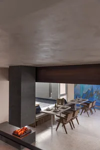 Industrial-style restaurant interior with concrete floor, wooden tables, and metal chairs.