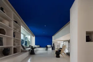 Minimalist living room with blue ceiling, white walls, and concrete materials.