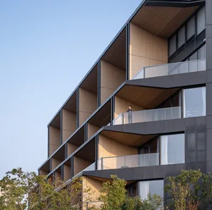 A minimalist residential building with a balcony featuring a specific cladding material.