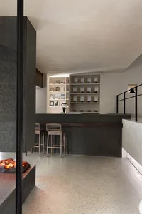 Modern coffee shop bar with a dark granite countertop and wooden stools.