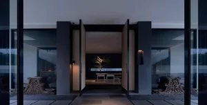 Modern entryway with glass walls and concrete walls featuring minimalistic design elements and lighting.