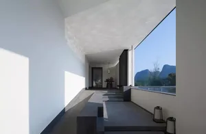 Modern entrance hall featuring a sleek glass wall with a view of mountains and sky.