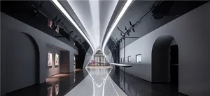 An expansive modern art gallery with glass walls, steel elements, and minimalist lighting.