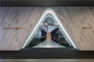Modern hotel entrance featuring marble walls, glass doors, and metallic accents.