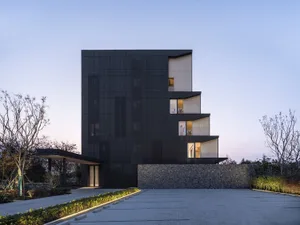 A modern office building with a black metal-clad exterior at dusk.