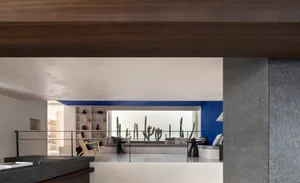 Modern residential interior with concrete walls and wooden ceiling beams.