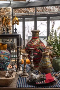A variety of decorative objects placed on a table, including vases, candles, and plants, with a bohemian aesthetic.