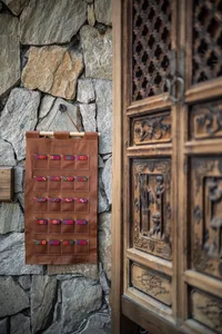 Brown leather decorative object with colorful patches hanging on a stone wall.