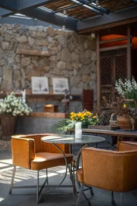 Industrial design outdoor cafe with wooden furniture, stone accents, and candlelight.