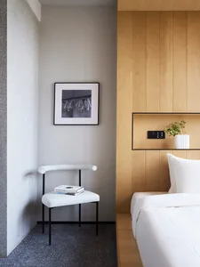 Modern minimalist bedroom with wood paneling and upholstered furniture.