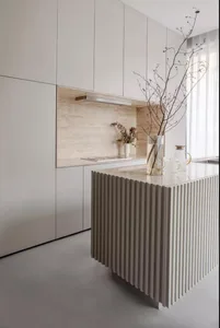 Minimalist kitchen with white walls, a white ribbed kitchen island, and a marble backsplash.