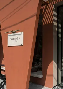 Facade of a minimalist storefront with concrete walls and a sign reading 'sanyea'.