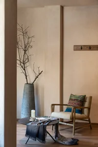 A modern living room featuring a comfortable upholstered chair with a cushioned seat, a round table covered with a grey fring