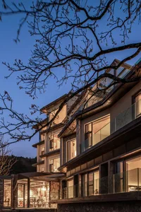 Modern residential buildings with glass and stone exteriors at dusk.