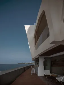 A modern restaurant exterior with a concrete facade overlooking the ocean.