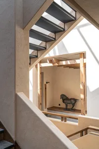 Industrial-style staircase with concrete steps and steel railings, featuring an abstract sculpture of a horse in the backgrou