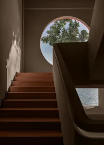 A staircase leading to a garden view through a circular window.