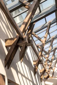 A modern architectural interior design featuring exposed wooden beams with intricate geometric patterns.