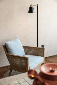 Modern living room with blue cushioned armchair, wooden legs, and floor lamp