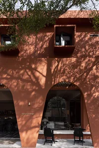 A modern building with a clay-stone exterior featuring a terrace and seating area.