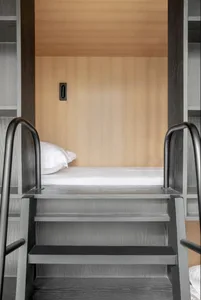 Modern minimalist bedroom featuring a wooden platform bed with a single white pillow.