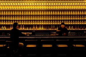 現代酒吧室內，牆面陳列著發亮的酒瓶。