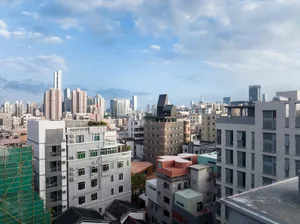 A modern cityscape featuring concrete, glass, and steel buildings against a partly cloudy sky.