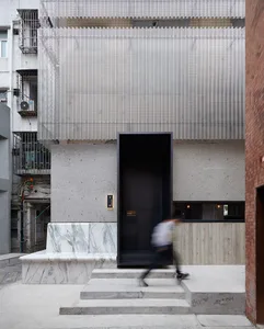 A modern, minimalist building entrance with concrete, marble, and metal elements