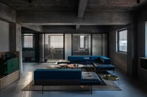 Modern industrial living room with concrete walls and ceiling beams.