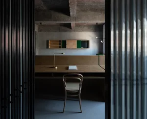 Industrial-style workspace featuring a wooden desk, chair, and minimalist shelving unit.