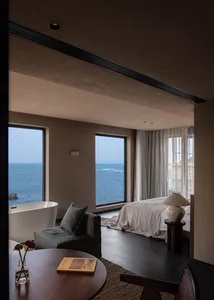 Modern minimalist bedroom with concrete floor, glass windows, and textiles