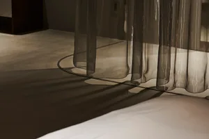 A minimalist interior with transparent curtains allowing natural light to filter through.