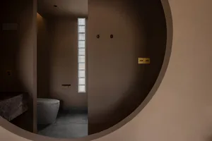 A modern bathroom with concrete flooring and walls, minimalistic design elements, and a sleek toilet.