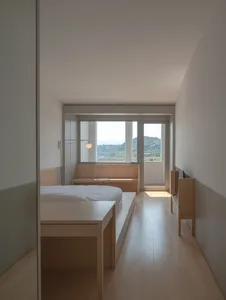 Modern bedroom featuring a wooden bed and bench with a view of the mountains through the large window.