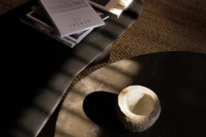 A modern coffee table with a stone vase and magazines.