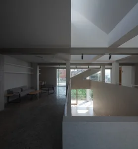 A modern, minimalist living room features concrete flooring and walls, with a focus on clean lines and a spacious, airy atmos