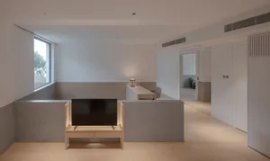 A modern interior living room with concrete flooring, minimalist furniture, and a large window.