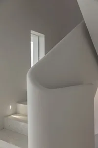 Modern staircase with a concrete railing and light wall, featuring a window.