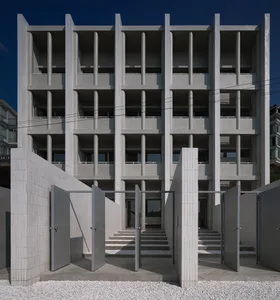 A modernist building with a concrete facade and vertical columns, featuring balconies and large windows.