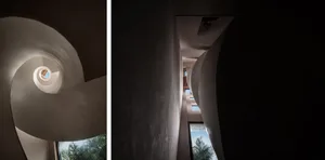 A spiral staircase with concrete walls and a window at the top