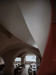 工業風餐廳室內，採用陶土與玻璃材質，搭配現代拱門及海景座位區。