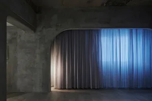 A modern interior design featuring luxurious drapery and concrete architectural elements.