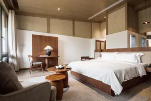 A minimalist bedroom featuring solid wooden furniture, glass elements, and neutral tones.