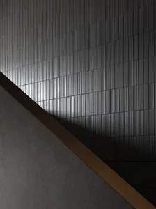 A minimalist interior featuring grey tiles with a diagonal light and shadow pattern.