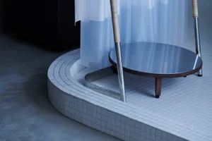 A modern bathroom featuring a circular metal tray and a white tiled floor with a circular ceramic tile design.