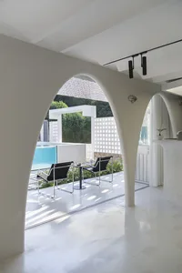 White concrete interior with arched doorways, minimalist design, and modern furniture.