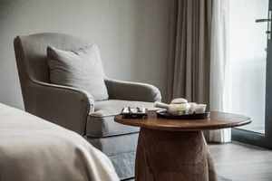 A modern living room featuring comfortable cushioned furniture and a wooden side table with a teapot and cups on it.